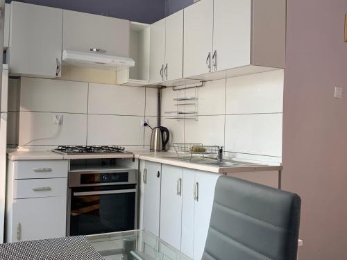 La cuisine est équipée de placards blancs et d'un four avec plaques de cuisson. dans l'établissement Apartament Leśne, à Bydgoszcz