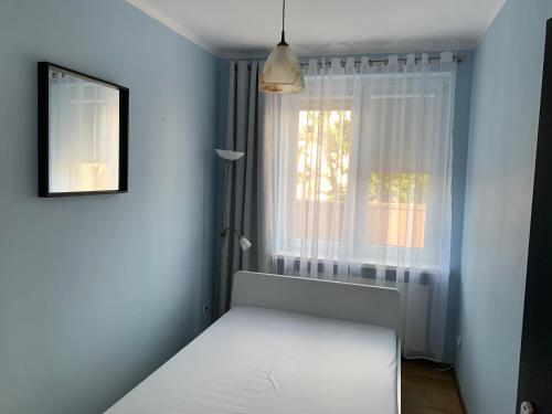 1 dormitorio con cama blanca y ventana en Apartament Leśne, en Bydgoszcz