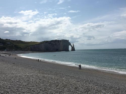 Un groupe de personnes marchant sur une plage près de l'océan dans l'établissement Le vieux logis, à Étretat