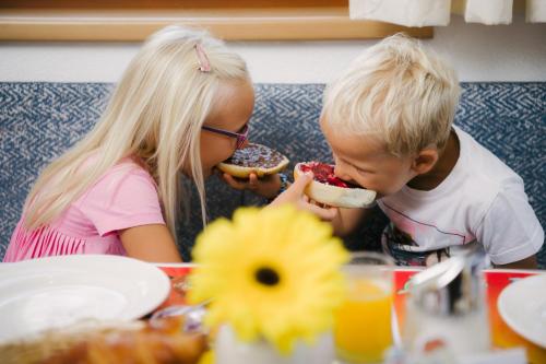 a boy and girl eating donuts at a table at Kinderhotel Laderhof in Ladis