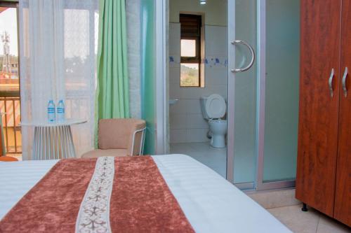 a bedroom with a bed and a bathroom with a toilet at Jarin Hotel in Kampala