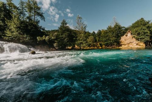 a river with blue water and trees in the background at Hotel Kostelski Buk in Bihać