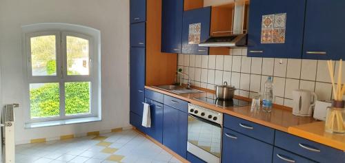 eine Küche mit blauen Schränken und einem Fenster in der Unterkunft Ferienwohnung Leo Duisburg - Nähe Bahnhof in Duisburg