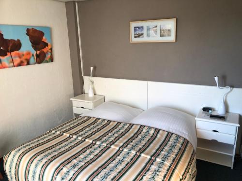 Schlafzimmer mit einem Bett mit gestreifter Decke in der Unterkunft Hotel Zee en Duin in Katwijk
