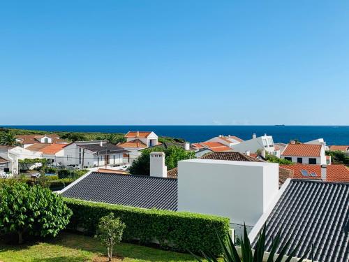 a view of roofs of houses and the ocean at Casa do O in Ponta Delgada