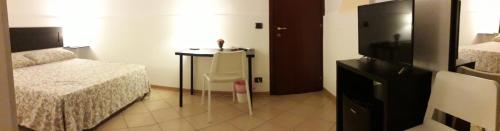a bedroom with a bed and a table and a tv at Fontanarossa Airport Home in Catania