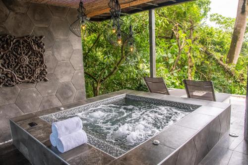 a jacuzzi tub in a patio with chairs at Makanda by The Sea Hotel Adults Only in Manuel Antonio
