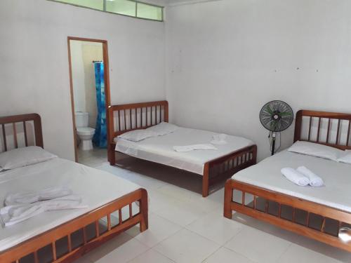a room with three beds and a fan at Hostal Zurymar Capurganá in Capurganá