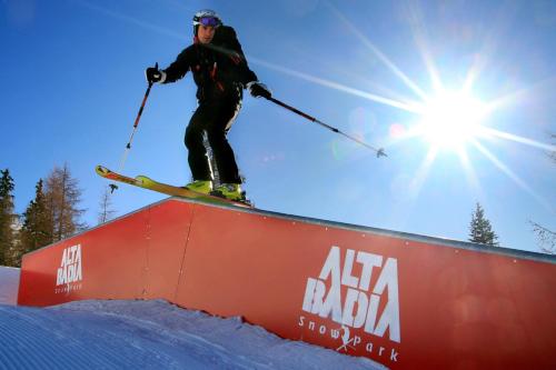a skier is jumping over a red rail at Hotel Ciasa Ai Pini in San Cassiano