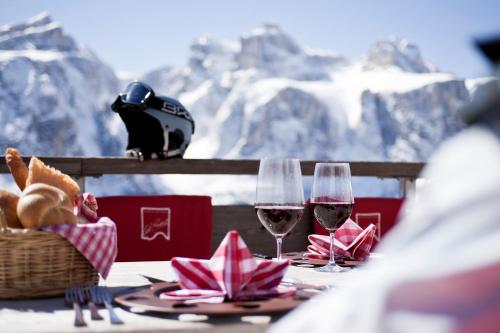 two glasses of wine sitting on a table with mountains in the background at Hotel Ciasa Ai Pini in San Cassiano