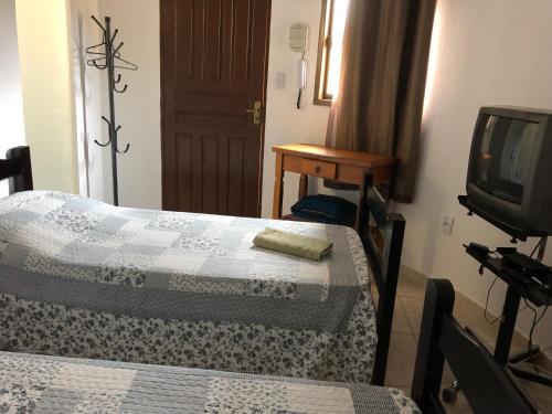 a room with two beds and a tv at Pousada Verde Maratea in Piranguçu