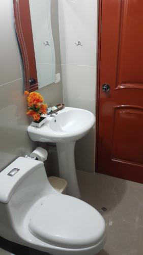 a bathroom with a white toilet and a sink at Hotel Los Nogales in Cajamarca