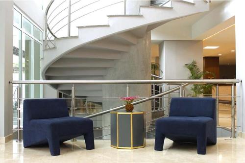 two blue chairs in a lobby with a staircase at Hesperia Maracay in Maracay