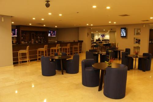 a restaurant with tables and chairs and a bar at Hesperia Maracay in Maracay
