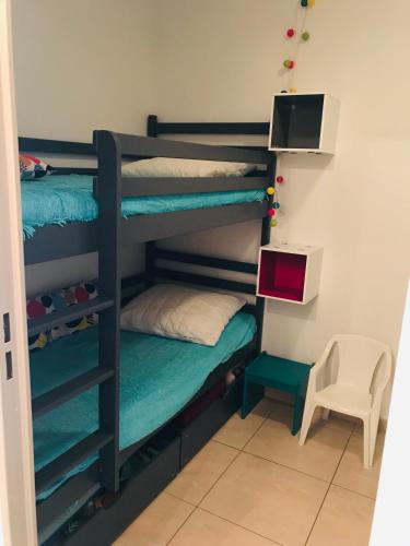 - une chambre avec des lits superposés, un bureau et une chaise dans l'établissement Appartement Cosy, au pied de la plage du Grazel., à Gruissan