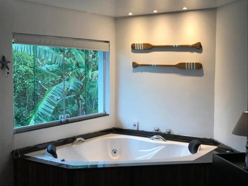 a bath tub in a bathroom with a window at Suites na Casa da Praia in Ilhabela