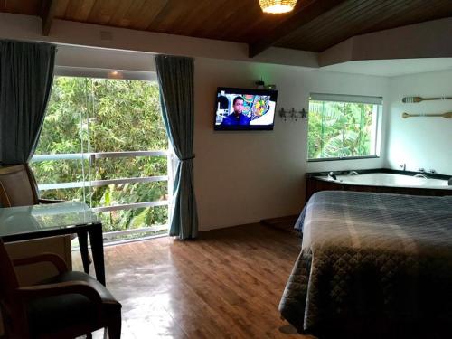 1 dormitorio con 1 cama y TV en la pared en Suites na Casa da Praia, en Ilhabela
