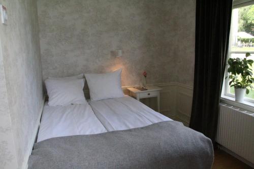 a bed with white sheets and pillows next to a window at Asa Herrgård in Asa