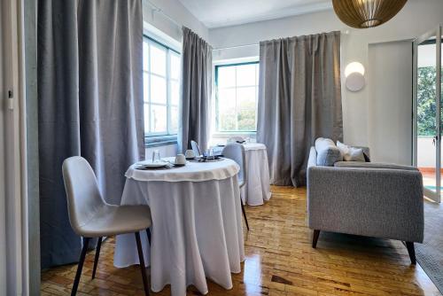 a living room with a table and chairs and windows at Comfy Sintra in Sintra