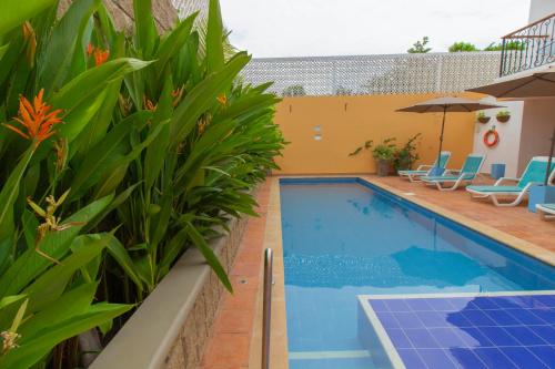 a swimming pool with blue chairs and an umbrella at Hotel La Gloria in Mompos