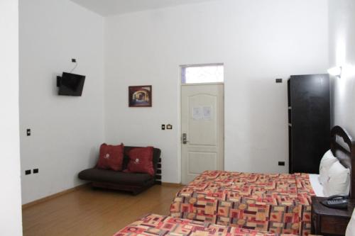 1 dormitorio con 1 cama, 1 silla y 1 puerta en Hotel La Alhondiga, en Puebla