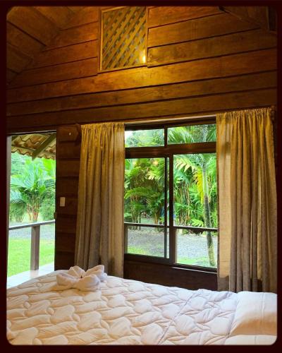 a bedroom with a bed and a large window at La Fortuna Waterfall Bungalows in Fortuna