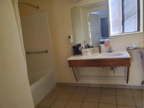 a bathroom with a sink and a tub and a mirror at Mission Inn San Luis Obispo in San Luis Obispo