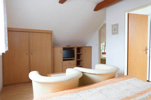 a bedroom with two white chairs and a bed at Penzion u lázní in Velké Losiny