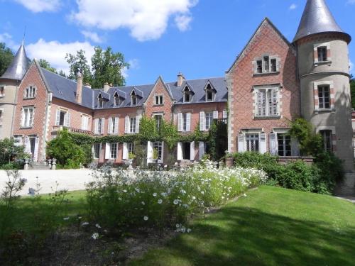 La Demeure d'Aglaë في Villeneuve-sur-Allier: مبنى من الطوب كبير مع ساحة عشب