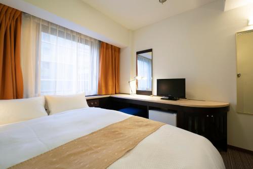 a hotel room with a bed and a desk with a computer at Hotel S-plus Nagoya Sakae in Nagoya