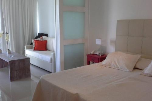 um quarto com uma cama, um sofá e uma cadeira em Green Park Apartamento con Balcón vista Lago em Punta del Este