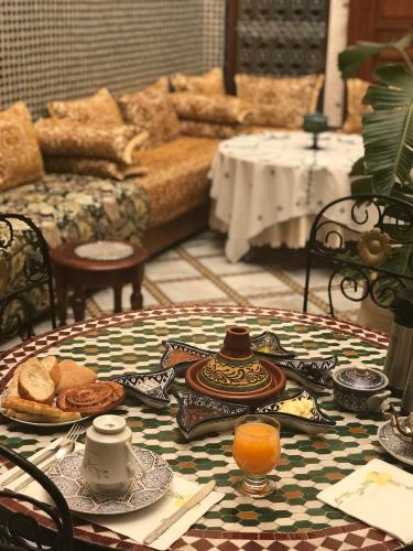 a table with a plate of food and orange juice at Riad Taj Salma in Fès
