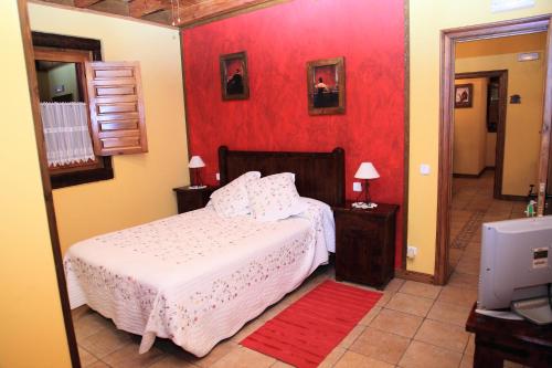 1 dormitorio con cama y pared roja en Posada la Vieja Escuela, en San Roque de Ríomiera