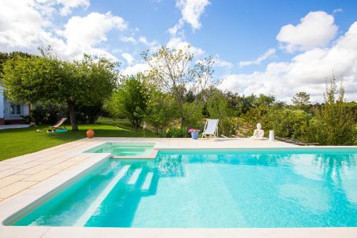 a swimming pool with blue water in a yard at Casa do Mundo in Calhariz