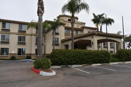 a building with palm trees in front of a parking lot at Studio 6 Carlsbad CA in Carlsbad