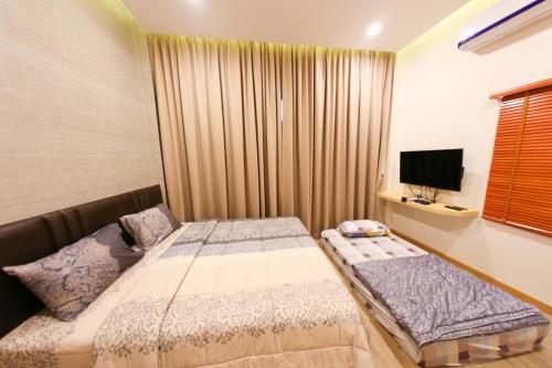 Habitación pequeña con 2 camas y TV. en Uzeason Poolvilla Sattahip en Sattahip