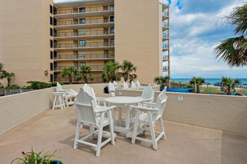 a patio with white chairs and tables and a building at The Top of the Gulf #112 in Panama City Beach