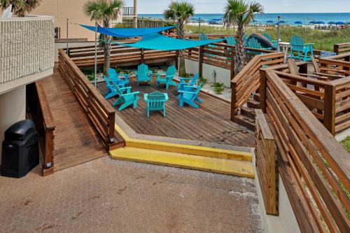 a deck with blue tables and chairs and the beach at The Top of the Gulf #112 in Panama City Beach