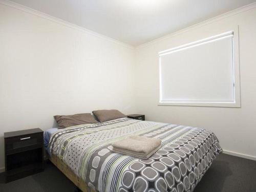 a white bedroom with a bed and a window at Agape Holiday Home with Pool table ,NBN Internet in Wallaroo