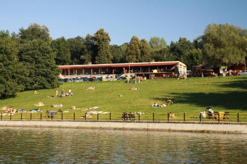 a group of people laying on the grass near the water at Restaurace penzion Pod Šumárníkem in Tvarožná Lhota