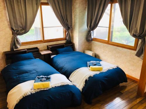 2 camas azules en una habitación con ventanas en Apartment at Toemu Nozawa, en Nozawa Onsen