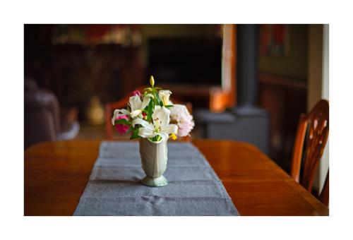 a vase filled with flowers sitting on a table at Oak Lodge in Greymouth