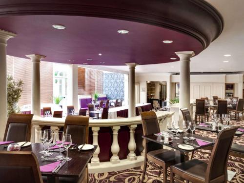 a restaurant with tables and chairs and purple ceilings at Mercure Dartford Brands Hatch Hotel & Spa in Ash