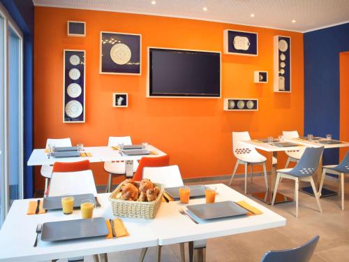 a dining room with tables and a flat screen tv at Ibis Styles La Louvière in La Louvière