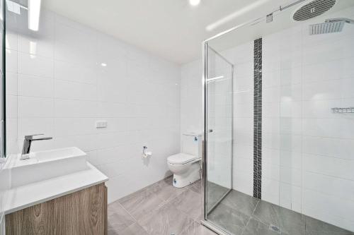 a bathroom with a toilet and a glass shower at Peppermill Inn Motel in Shepparton