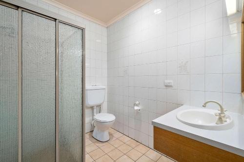 a bathroom with a shower, sink, and toilet at Peppermill Inn Motel in Shepparton