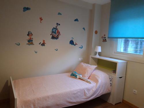 una piccola camera da letto con un letto e alcuni adesivi sul muro di Apartamento Covelo a Poio
