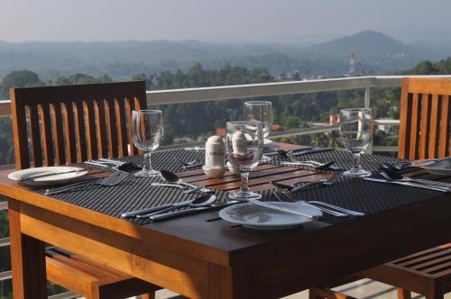 a table with wine glasses and plates on top of a balcony at Amaara Sky Hotel Kandy in Kandy