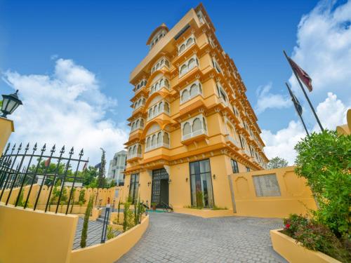a large yellow building with a fence at Sterling Balicha Udaipur in Udaipur