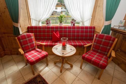 a living room with a red couch and two chairs and a table at Hotel Jägerhof in Kaunertal